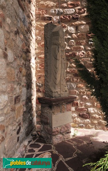 Escultura de Sant Oleguer, bisbe de Barcelona, amagada darrera un xipré a la dreta de la porta principal