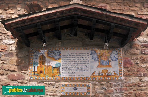 Santa Maria - Ceràmica a la façana que reprodueix part del pergamí que explica l'origen de l'Església, conservat a l'arxiu de la Corona d'Aragó